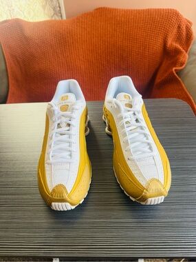 These are big kids Nike Shox R4 sneakers in a gold and white colorway.